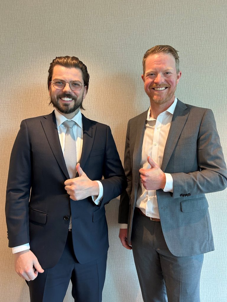 Roper Greyell Associate Steven Parker and Partner Brandon Hillis pose with thumbs up against a wall.
