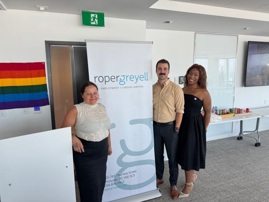 Jeylan Bishop, Michael Robach, and Gray Mmono from QMUNITY standing next to Roper Greyell banner.